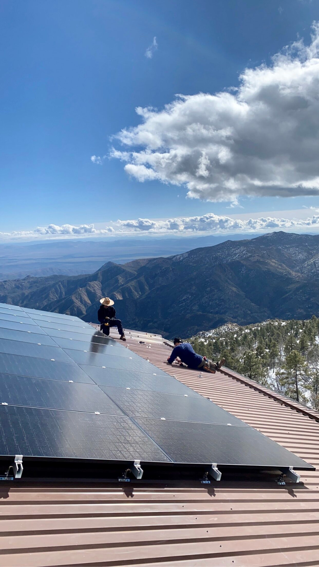 Technician on the roof-mounted solar array with mountain views